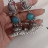 oxidized silver peacock jhumka earrings with turquoise stones and white pearl embellishments.