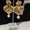 The earrings shown in the image are a style of traditional Indian jewelry known as Kundan or Polki earrings, often featuring a design with a pearl drop