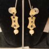 This is a pair of traditional Indian earrings with a gold-toned finish, black stones, and a pearl drop.